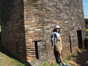 Full length of man standing against brick wall