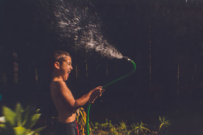 Boy playing with a hose in the backyard
