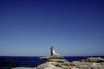 Statue by sea against clear blue sky