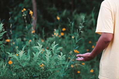 Midsection of man standing by flowering plants