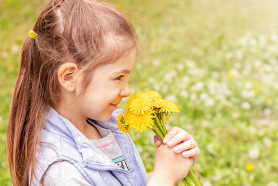 Cute girl smelling flowers at field