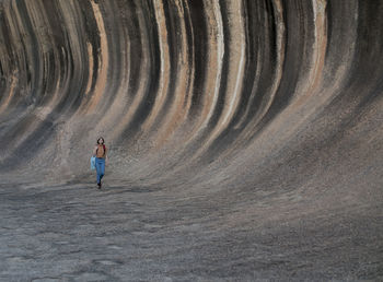 Full length of young woman walking by rock formations