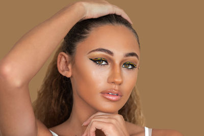 Close-up portrait of young woman against pink background