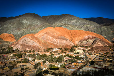 Aerial view of buildings in town against blue sky