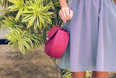 Midsection of woman holding pink while standing outdoors