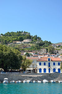 Buildings by sea against clear sky