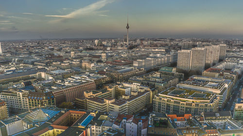 Fernsehturm amidst cityscape against sky during sunset