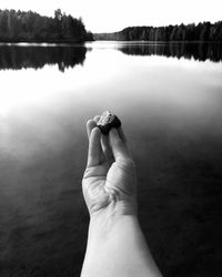 Close-up of hand on lake against sky