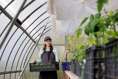 Low angle view of young woman standing in greenhouse