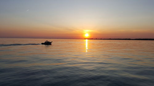 Silhouette boat sailing on sea against sky during sunset