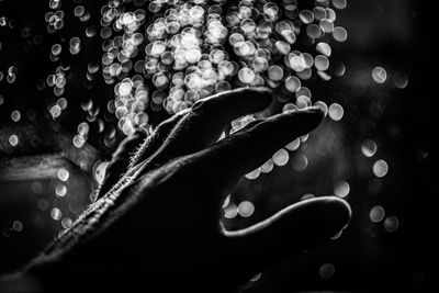 Close-up of woman hand in illuminated water at night