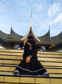 People sitting at temple against sky