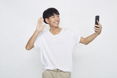 Portrait of smiling young man using smart phone against white background