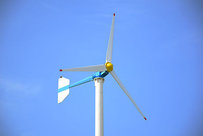 Low angle view of wind turbine against blue sky