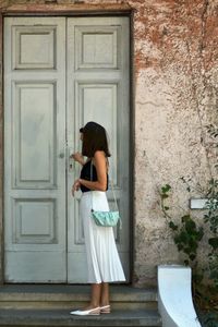 Rear view of woman standing against door of building