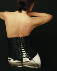 Rear view of woman standing against black background