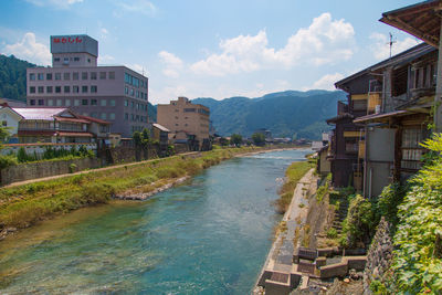 Buildings by river in town against sky