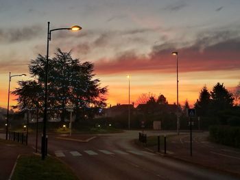 Road in city against sky during sunset