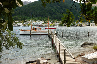 Boats moored on river by trees against sky