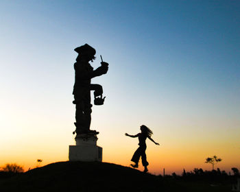Low angle view of man standing against clear sky during sunset