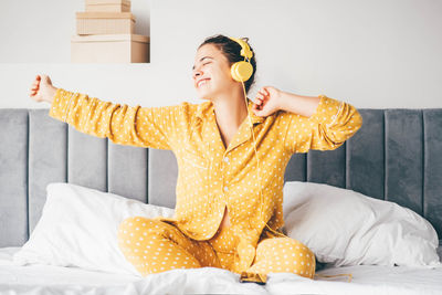 Portrait of young woman sitting on bed at home