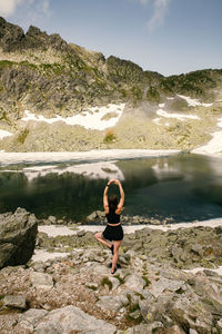 Full length of man standing on rock by lake