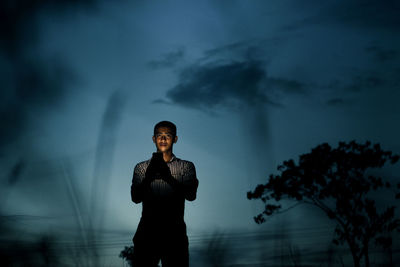 Man using mobile phone while standing against sky