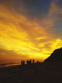 Silhouette people on beach against sky during sunset