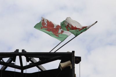 Low angle view of welsh flags against cloudy sky