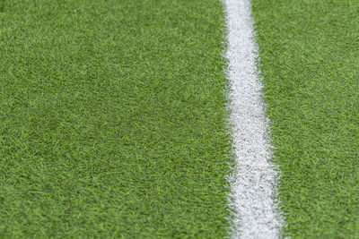 Green artificial grass soccer sports field with white stripe line.