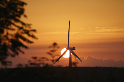 Wind turbines on field against sky during sunset