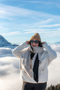 Portrait of young woman standing against sky