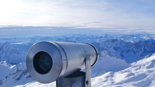 Coin-operated binoculars against snow covered mountains