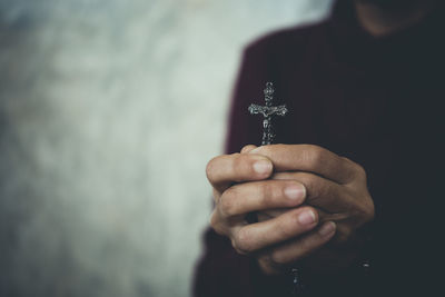 Midsection of person holding crucifix