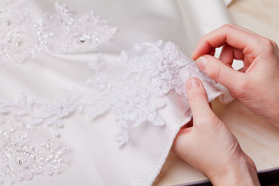 Cropped hands of woman stitching wedding dress