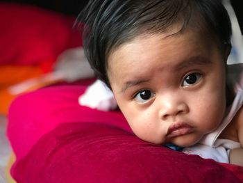 Close-up portrait of cute baby girl on bed at home