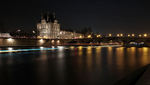 Illuminated bridge over river at night