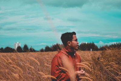 Young man standing on field against sky