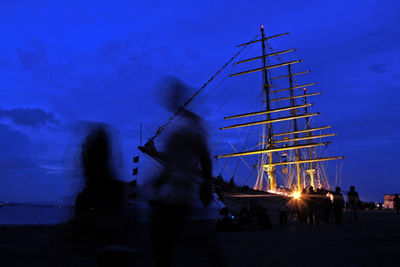 People on illuminated boat against sky at night