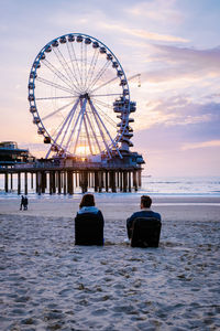 Rear view of people on beach at sunset