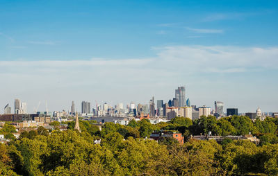 Trees and buildings in city against sky