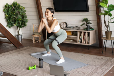 Full length of young woman exercising on table