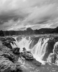 Scenic view of waterfall against sky