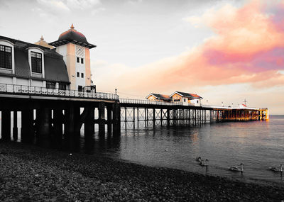 Pier over sea against sky during sunset