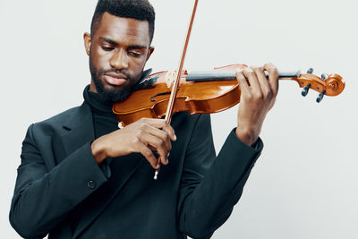 Midsection of man playing violin against white background