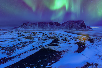 Scenic view of snowcapped mountains against sky at night