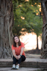 Portrait of woman sitting on tree trunk