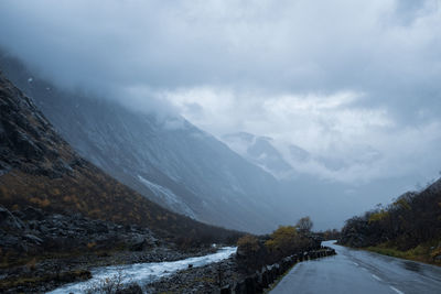 Romsdalen valley in norway with highway and mist on mountaintops. vanishing point.