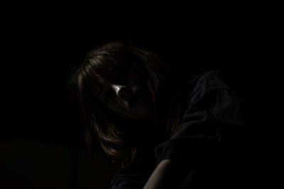 Close-up of young woman against black background