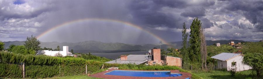 Panoramic view of rainbow over buildings against sky
